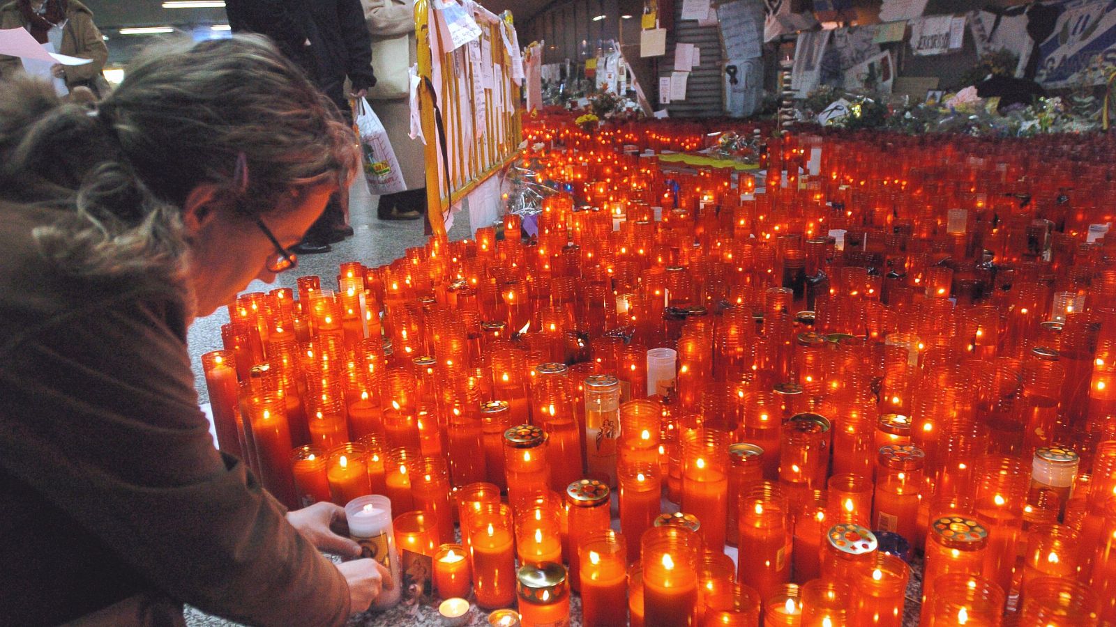 Una joven deja una vela en recuerdo de las víctimas del atentado del 11-M.