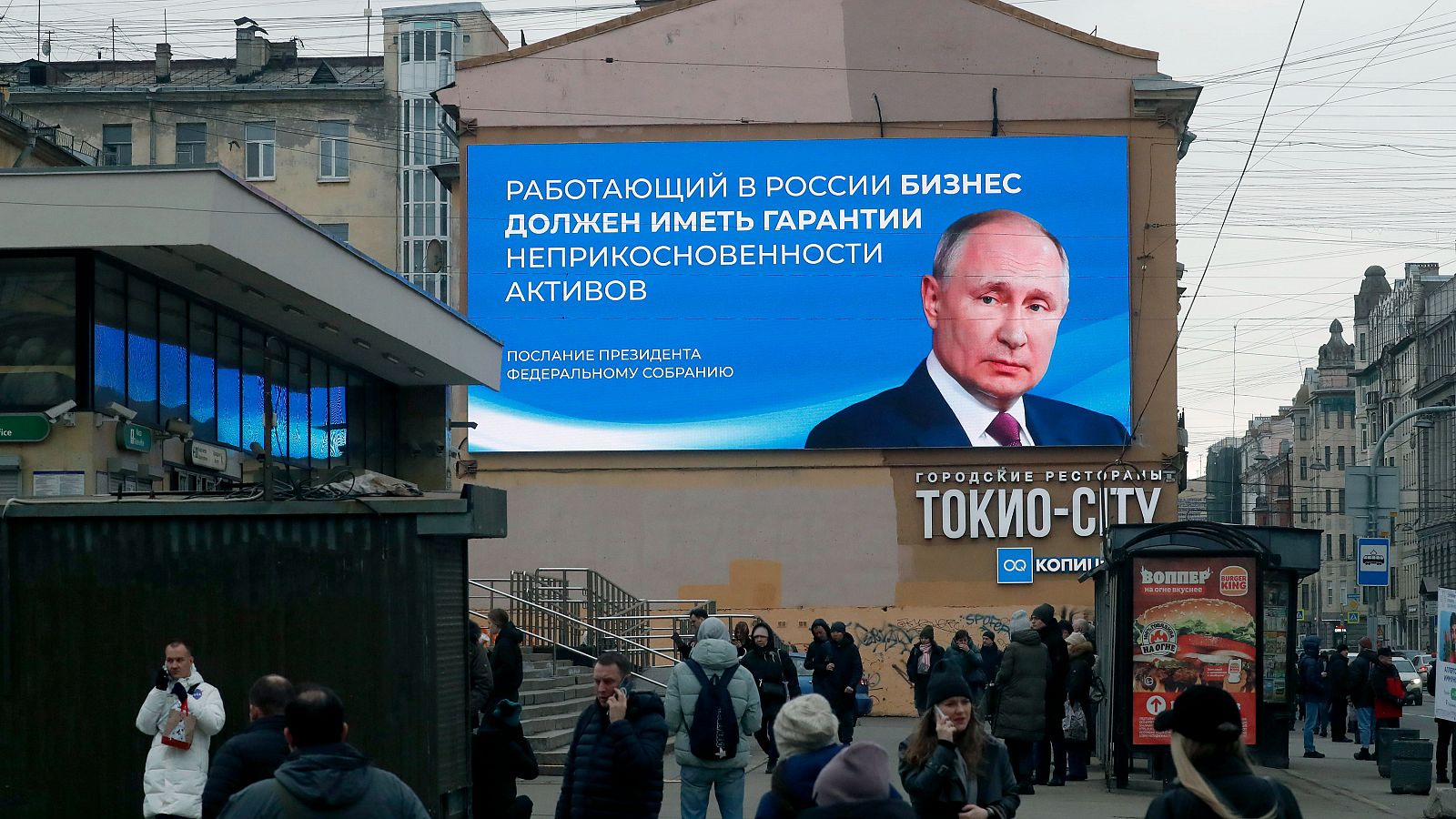 Elecciones en Rusia 2024: Ciudadanos rusos pasa junto a un enorme cartel digital que muestra a Vladímir Putin