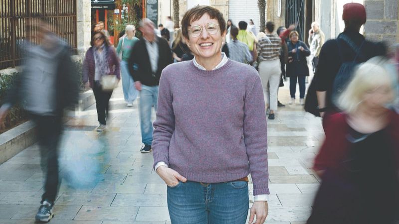 Una mujer sonríe por la calle rodeada de gente desenfocada