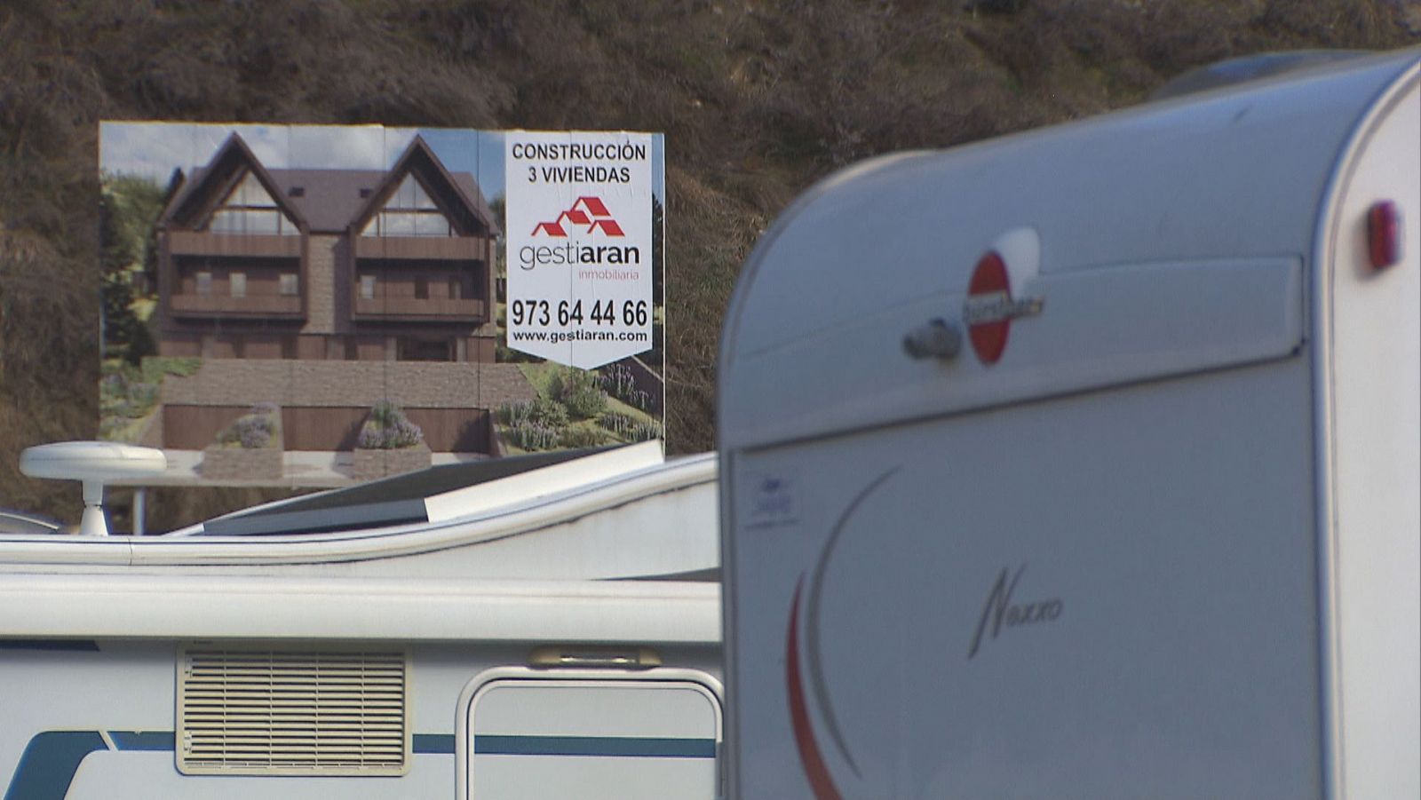 Caravanas con fondo de carteles de construcción de chalets en Baqueira, Valle de Arán.