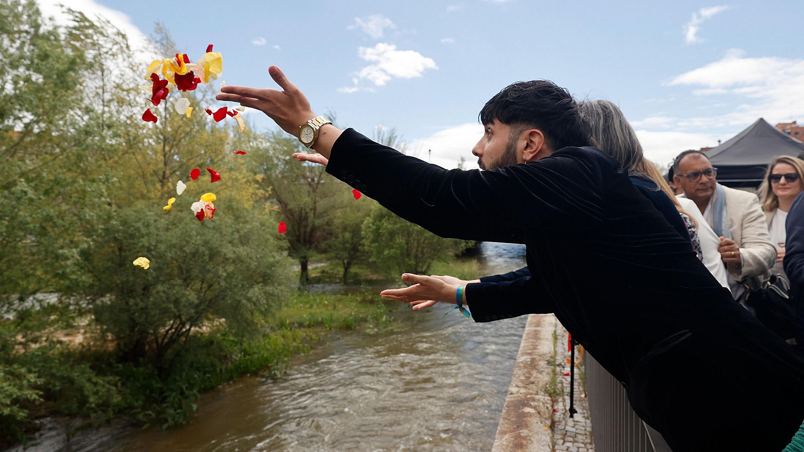 Unas personas lanzando pétalos al río Manzanares por el día Internacional del Pueblo Gitano