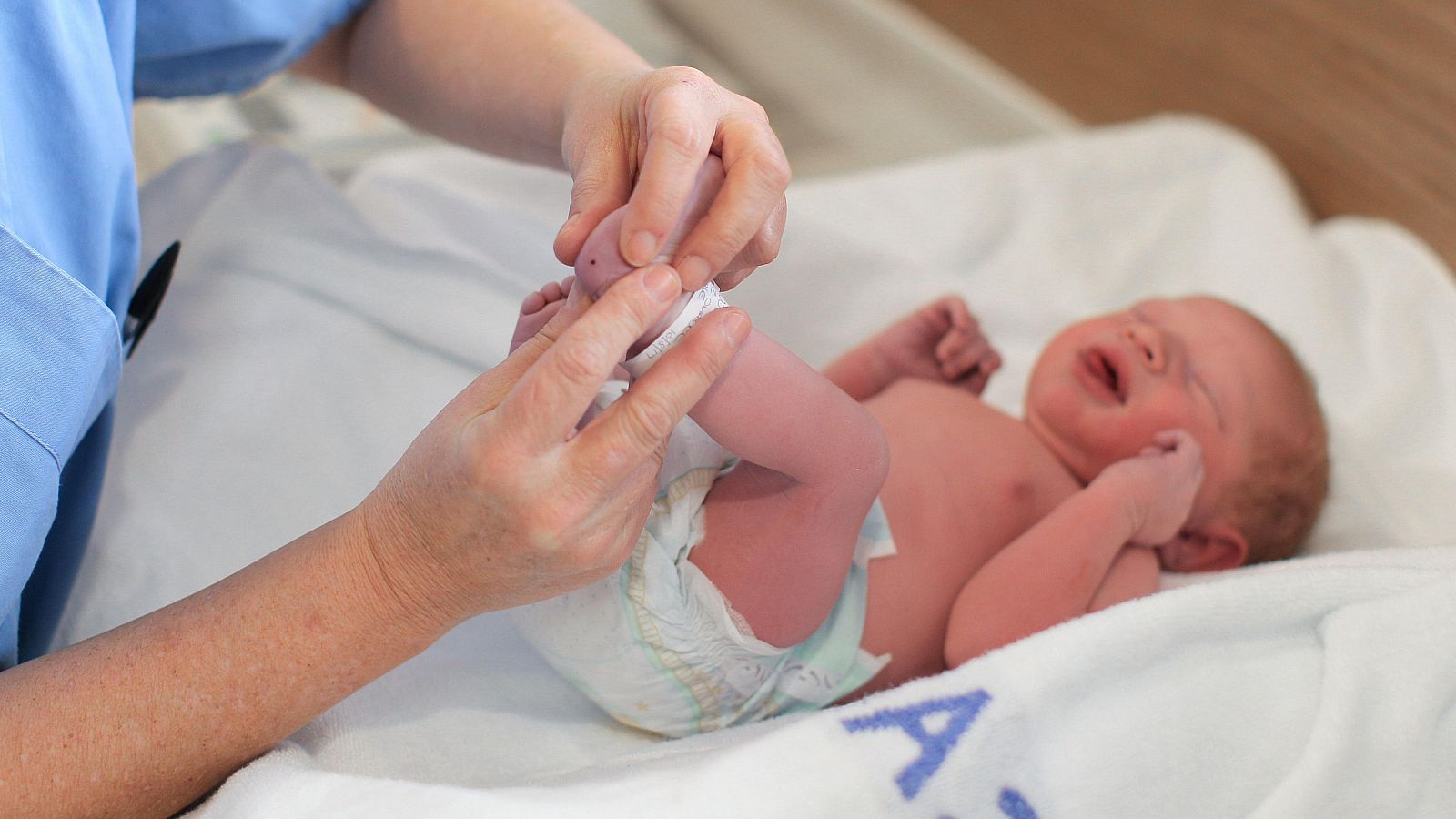 Un sanitario realiza la prueba del talón a un bebé
