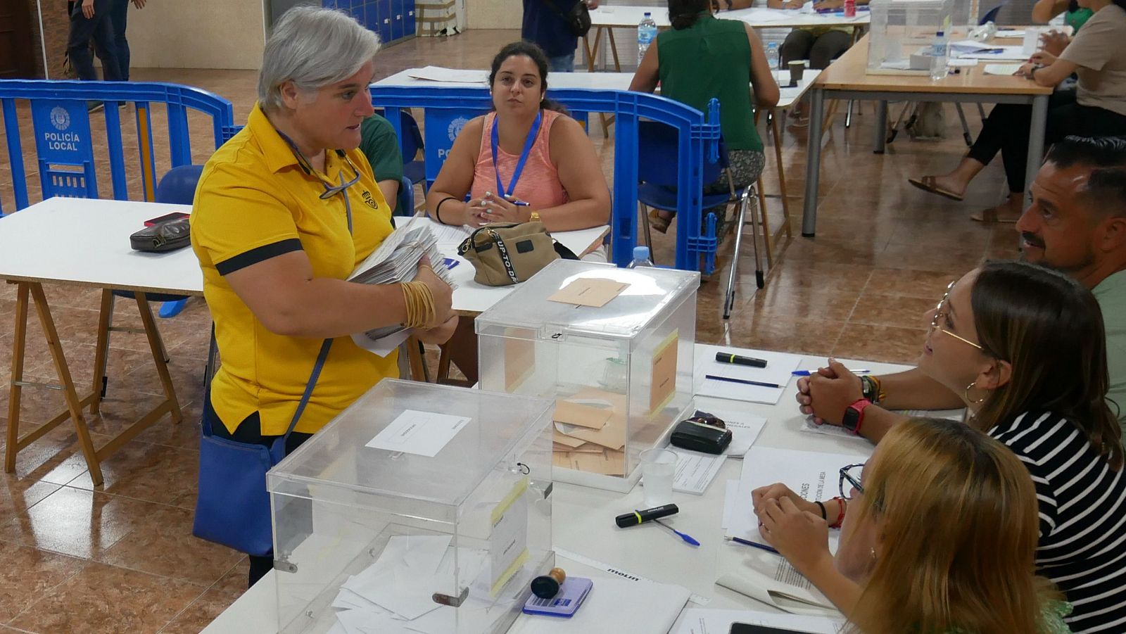 Una funcionaria de Correos entrega los votos por correo en una mesa electoral.