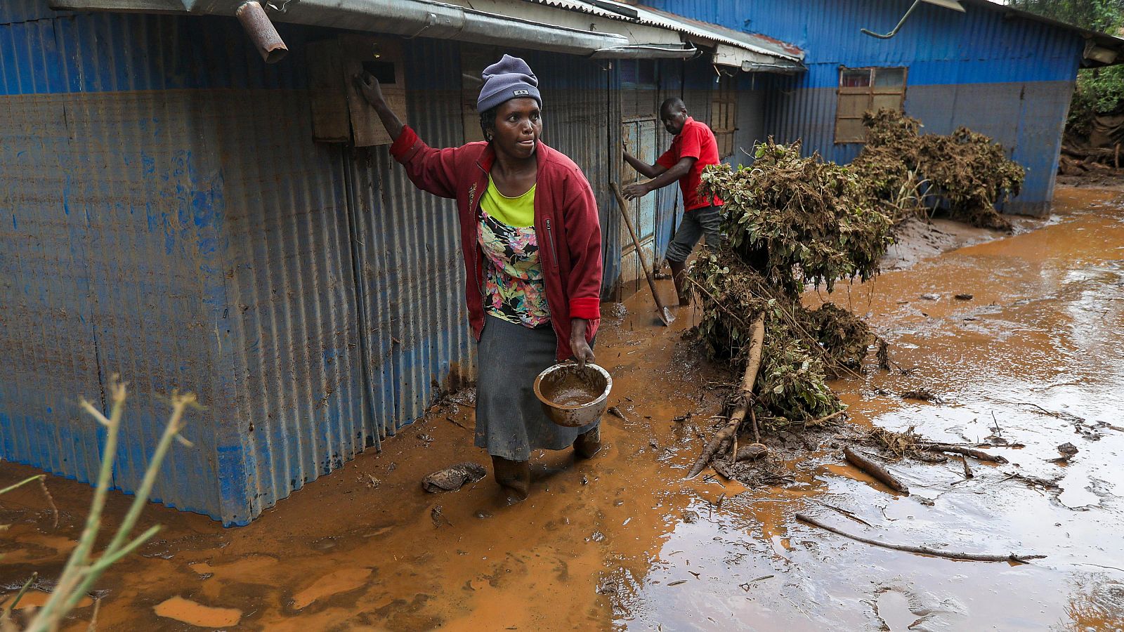 Dos personas limpian los alrededores de su casa en Kenia tras una inundación