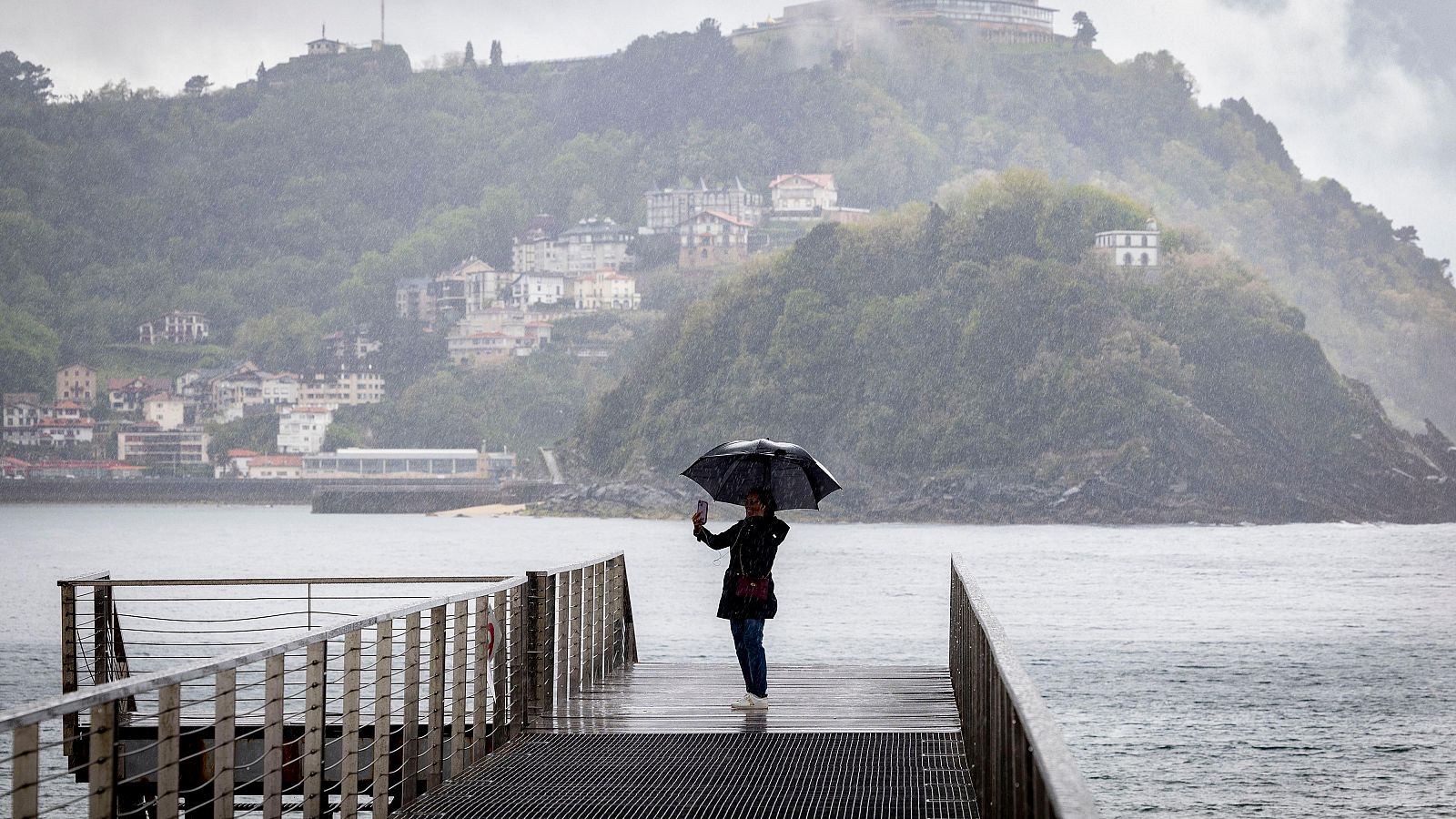 Una mujer con un paraguas en la pasarela del Náutico de San Sebastián