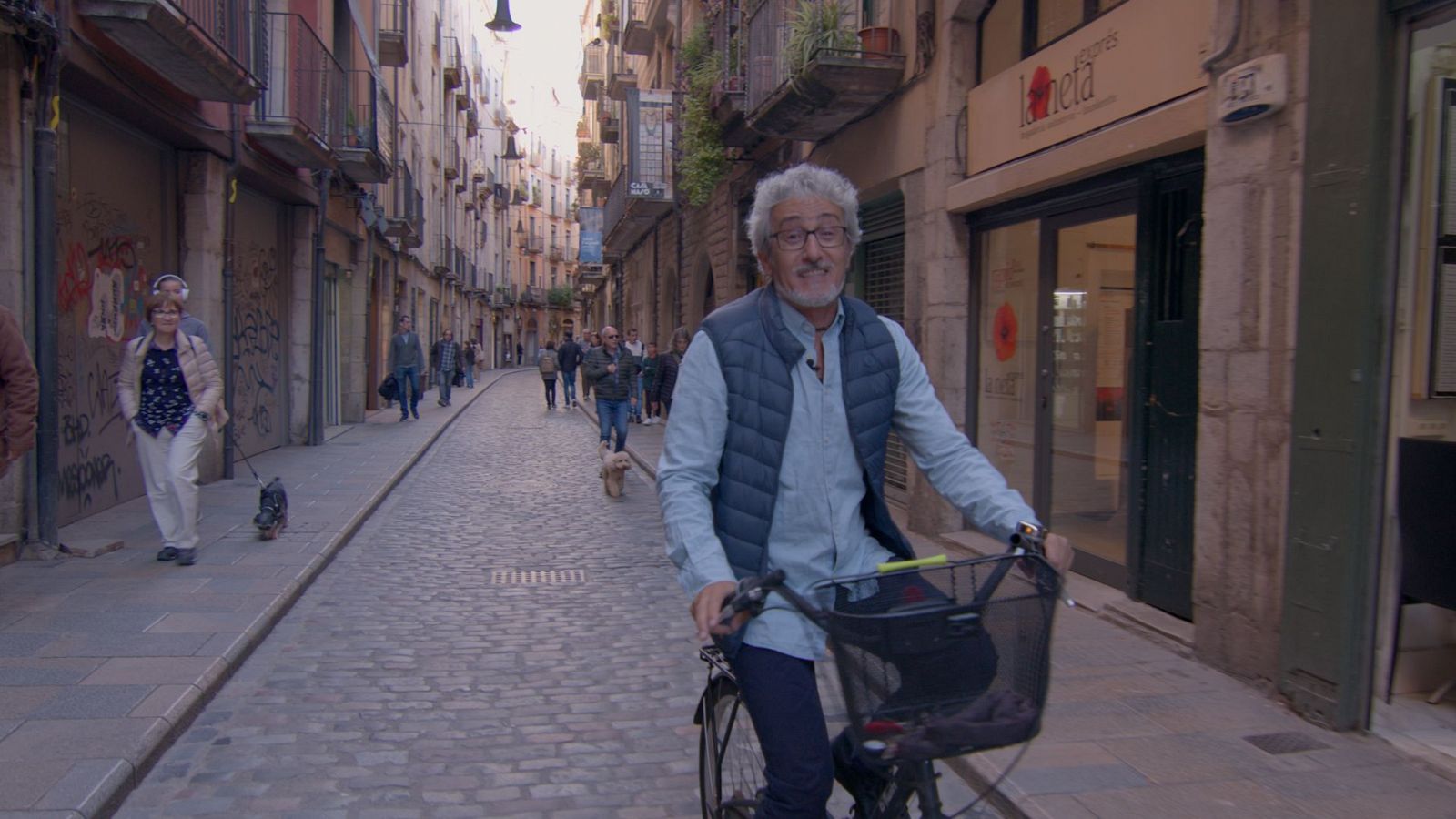 El presentador David Fernández passejant en bicicleta al carrer de les Ballesteries de Girona