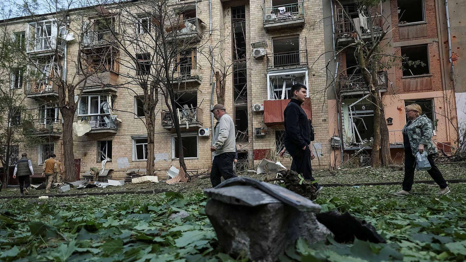 Varias personas pasan junto a un edificio dañado por las bombas en Járkov