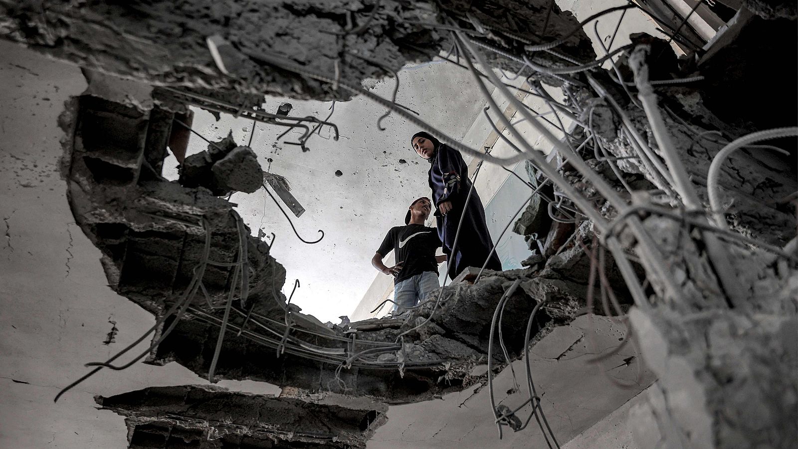 Dos personas miran un gran agujero en el techo de una escuela de Naciones Unidas para refugiados palestinos en Gaza