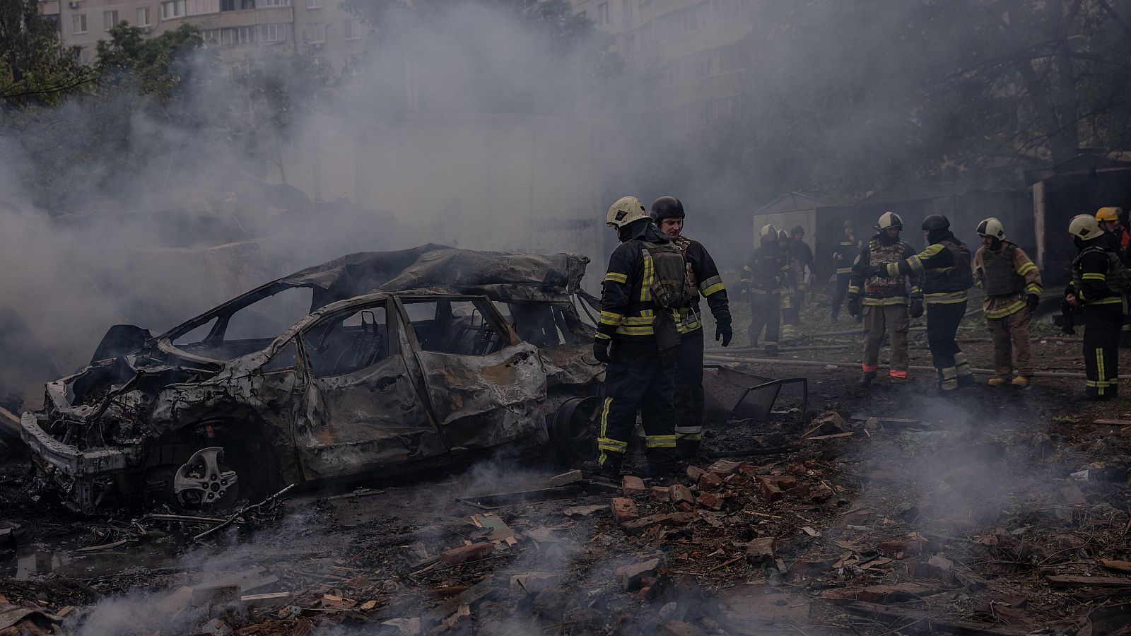 Bomberos ucranianos caminan entre los escombros frente a un edificio residencial dañado como resultado de un ataque con misiles en Járkov