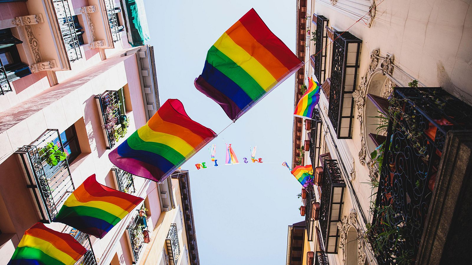 Varias banderas LGTBI+ colgadas entre dos edificios en Madrid