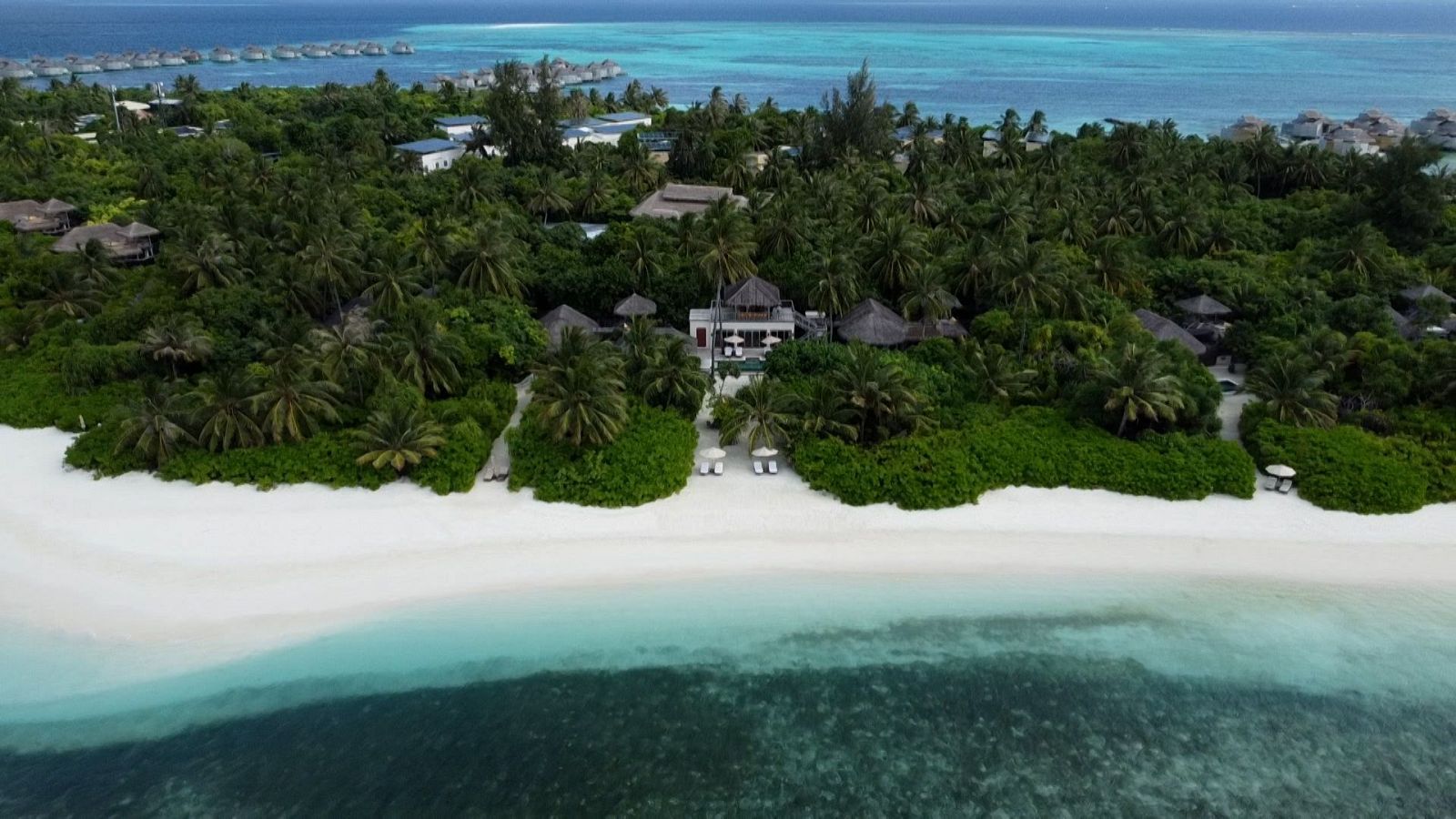 isla repleta de árboles con bungalós y rodeada de playas blancas y agua turquesa