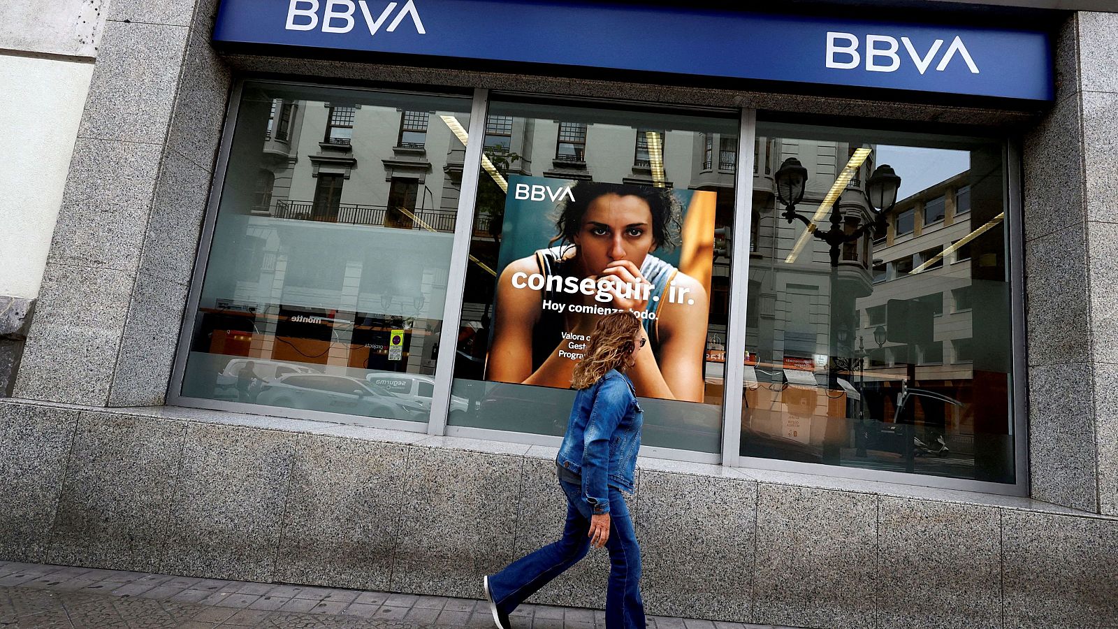 Una mujer pasea delante de una oficina del BBVA