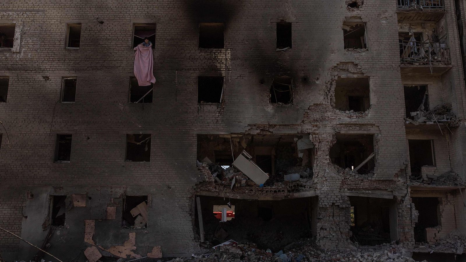 Una mujer limpia los escombros de su apartamento de un edificio residencial dañado tras un ataque aéreo ruso