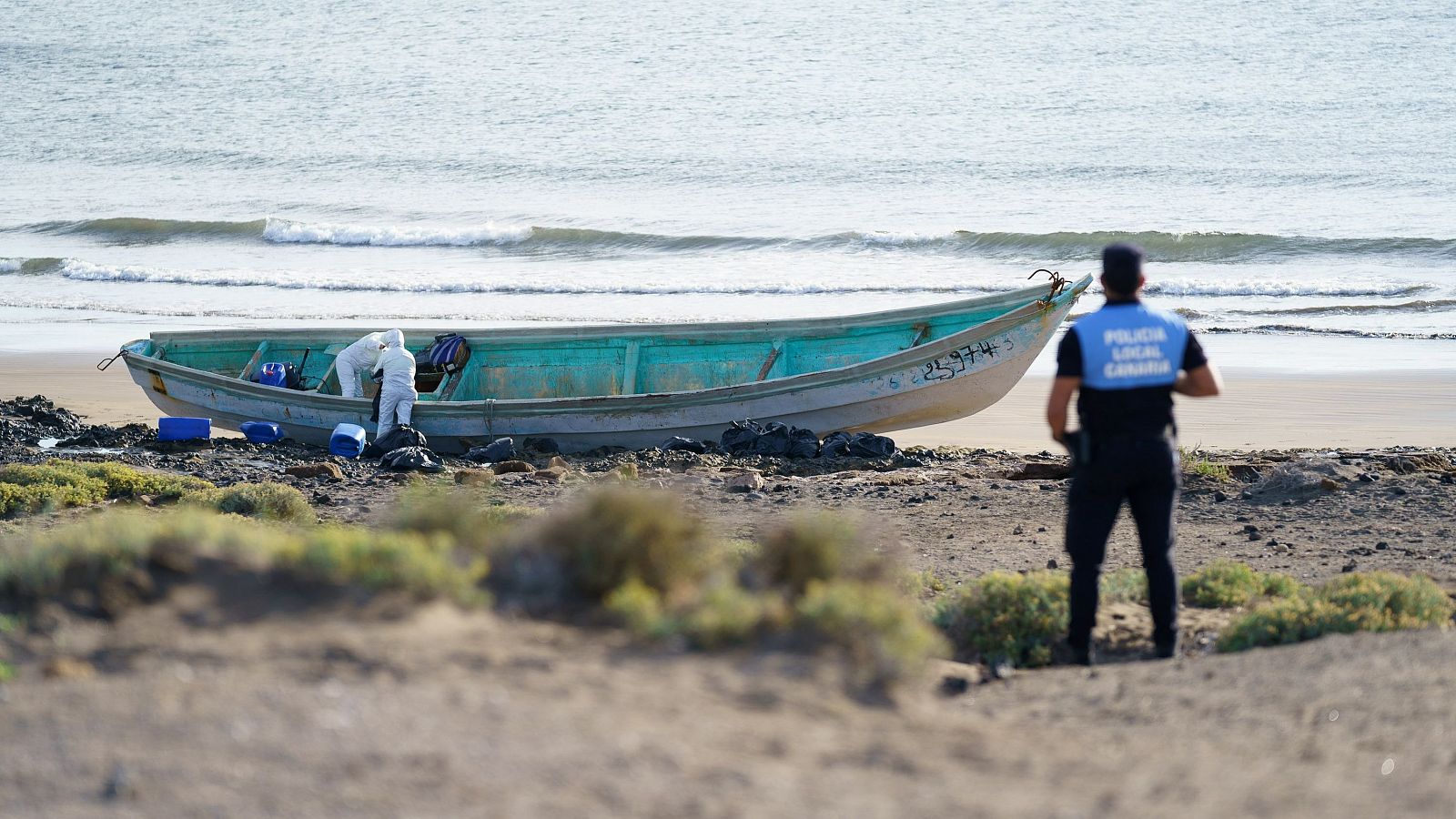 Un agente vigila una patera vacía en una playa al sur de Tenerife