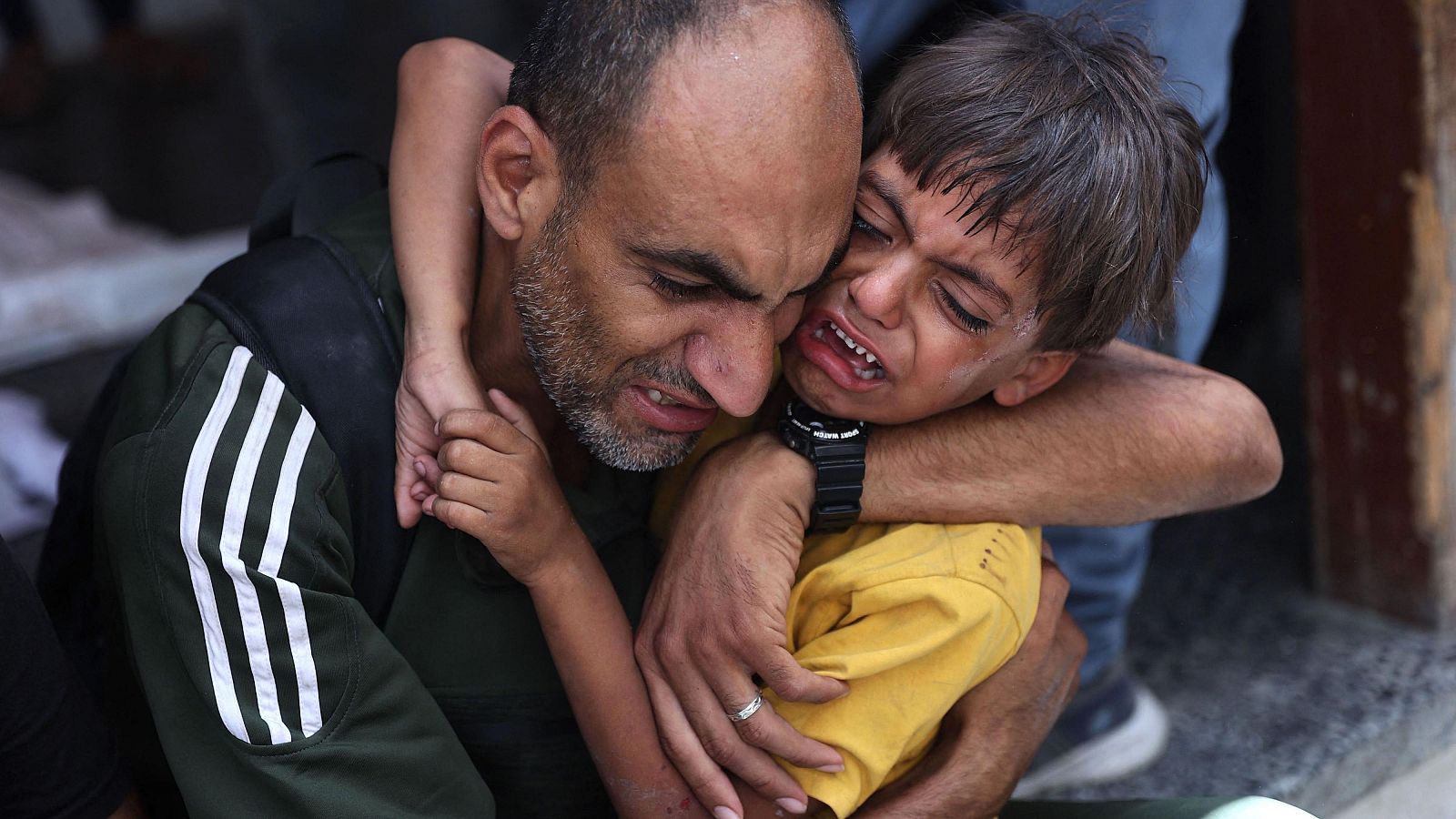 Un niño palestino recibe consuelo mientras está cerca de una bolsa para cadáveres (invisible) tras el bombardeo israelí de un barrio de la ciudad de Gaza, en el hospital árabe Al-Ahli