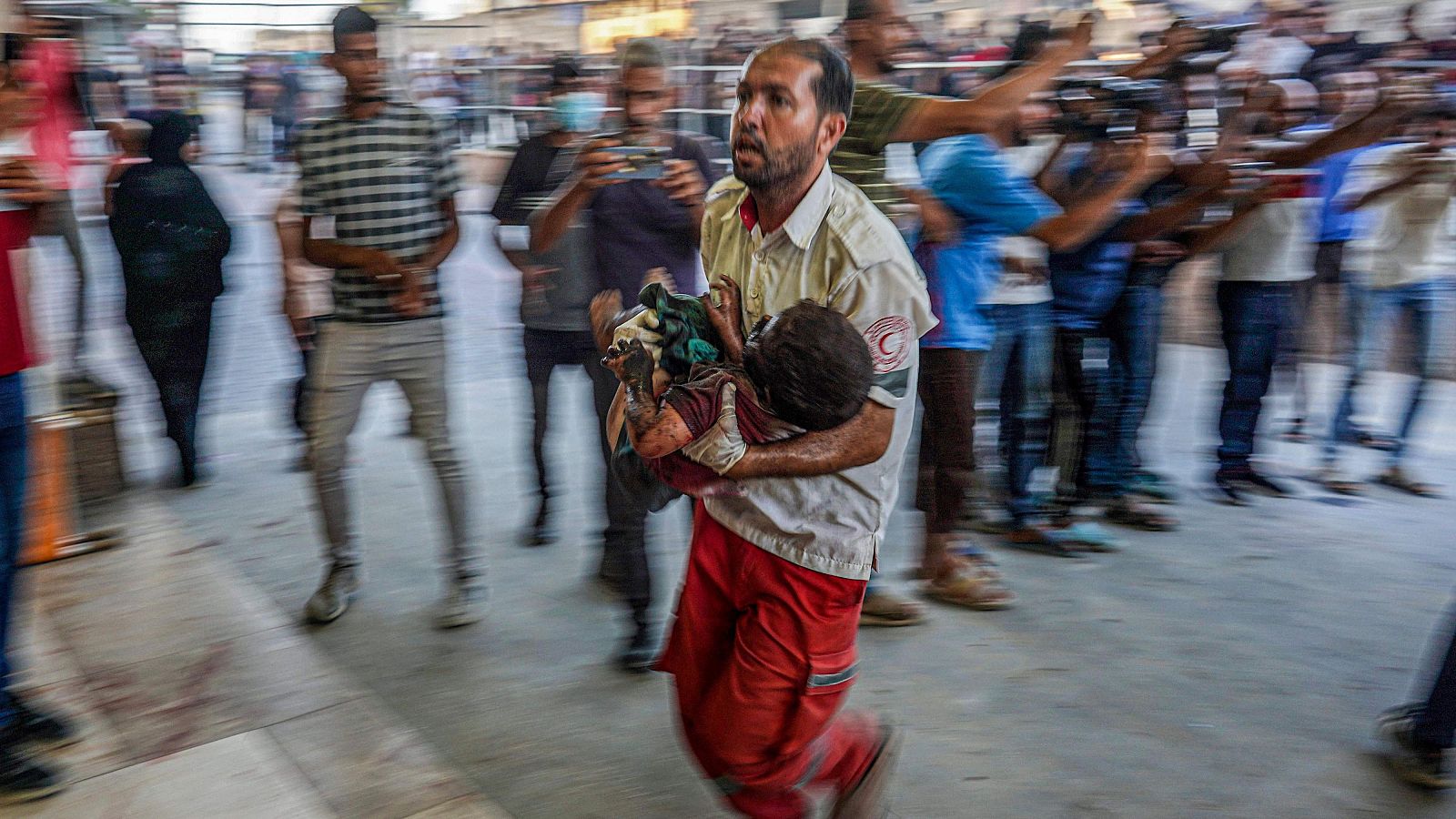 Israel bombardea otra escuela en Gaza y mata a 29 personas. Imagen: un sanitario de la Media Luna Roja lleva a un niño al hospital de Jan Yunis.