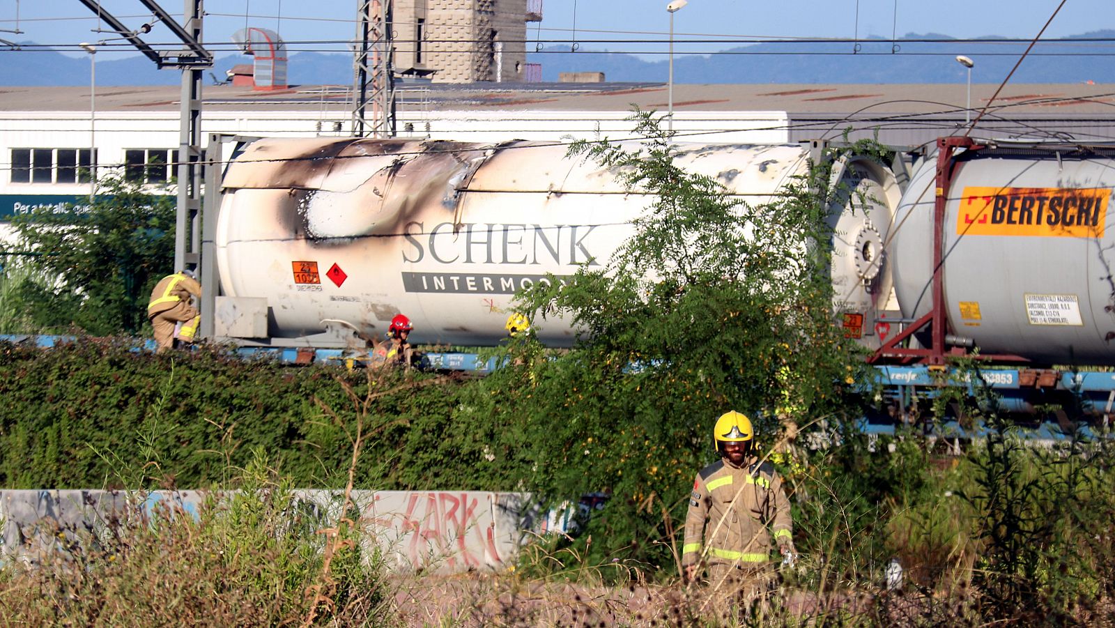 Els Bombers al costat del vagó del tren de mercaderies que s'ha incendiat a Girona