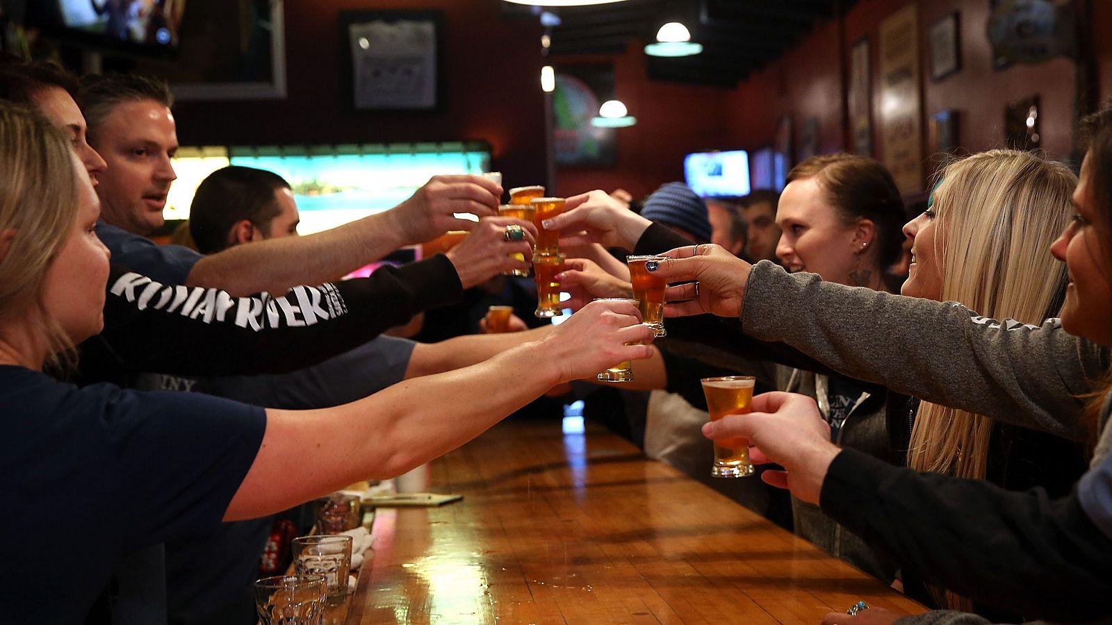 Un grupo de jóvenes bebe cerveza en un pub