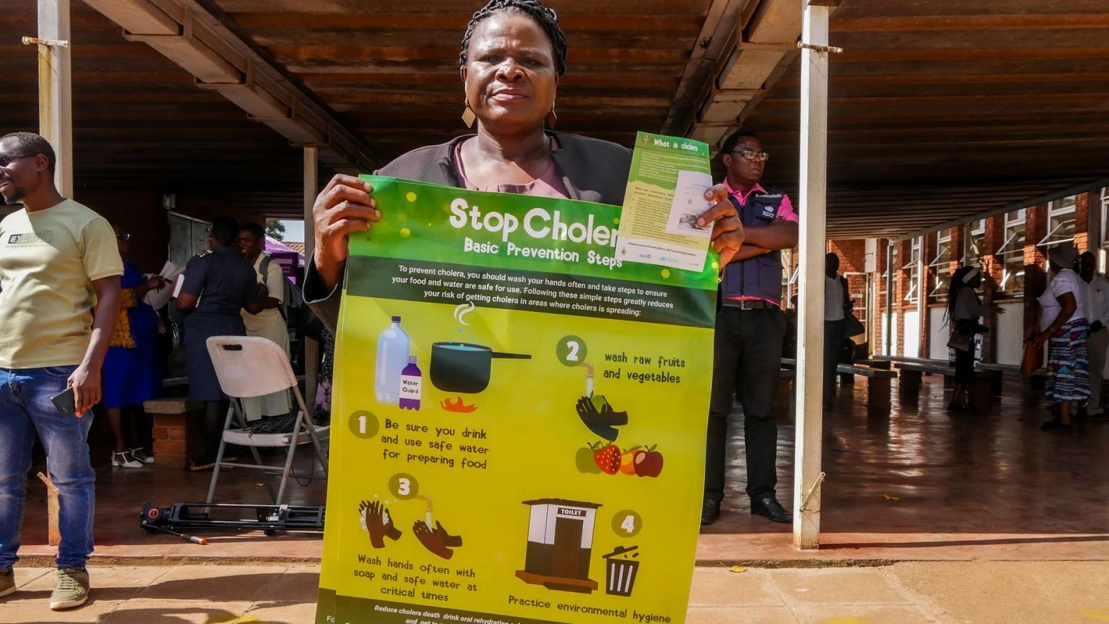 Una mujer muestra un póster informativo para prevenir el cólera en Zimbabue.