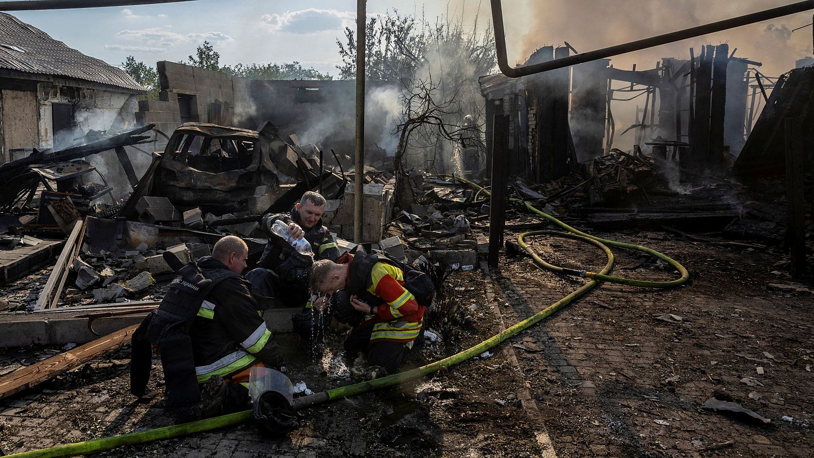 Trabajadores de emergencias se refrescan después de extinguir un incendio tras un ataque ruso