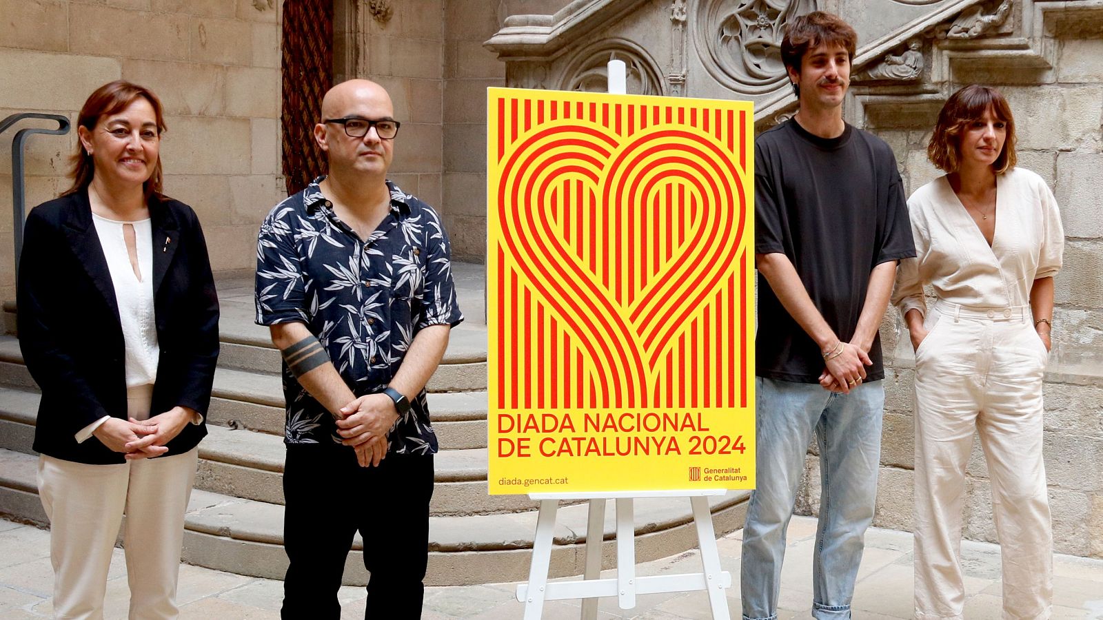 La portaveu i consellera del Govern, Sílvia Paneque, amb el cartell institucional de la Diada, acompanyada de diversos creadors de l'acte i la imatge