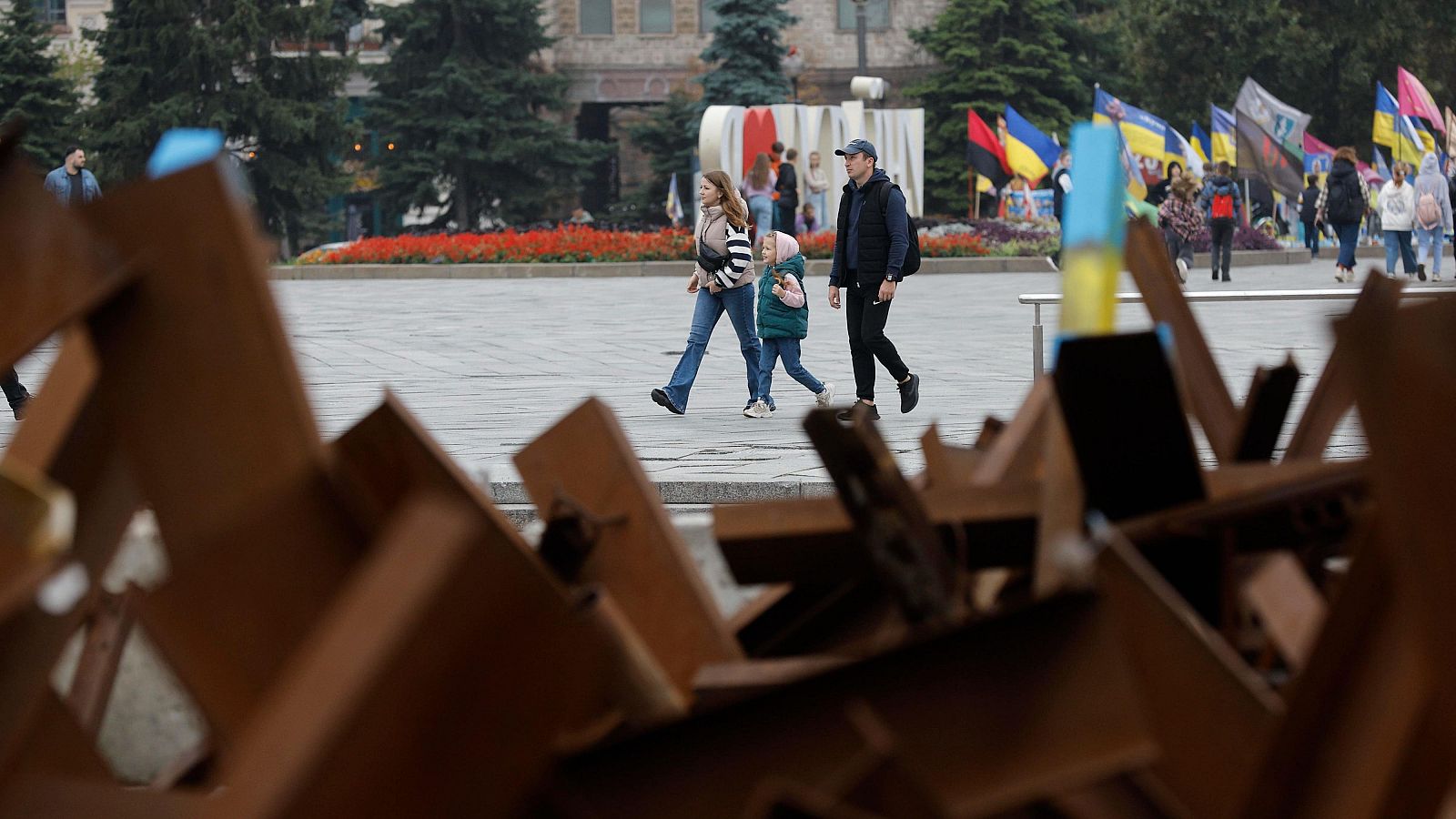 Un grupo de transeúntes ucranianos camina detrás de erizos checos ubicados en la Plaza de la Independencia en Kiev