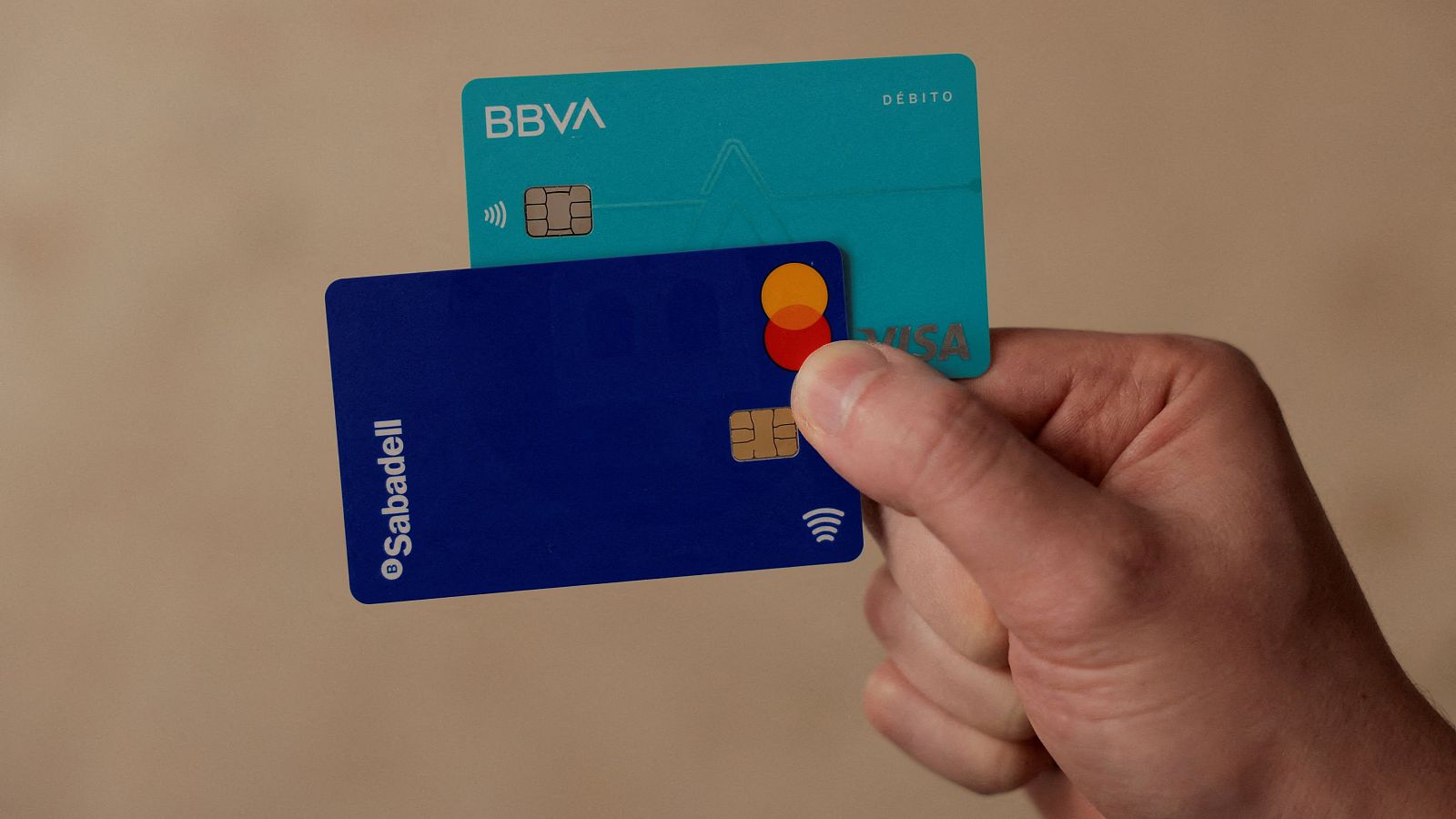 Una persona sujeta dos tarjetas de débito, una del Banco Sabadell y otra de BBVA