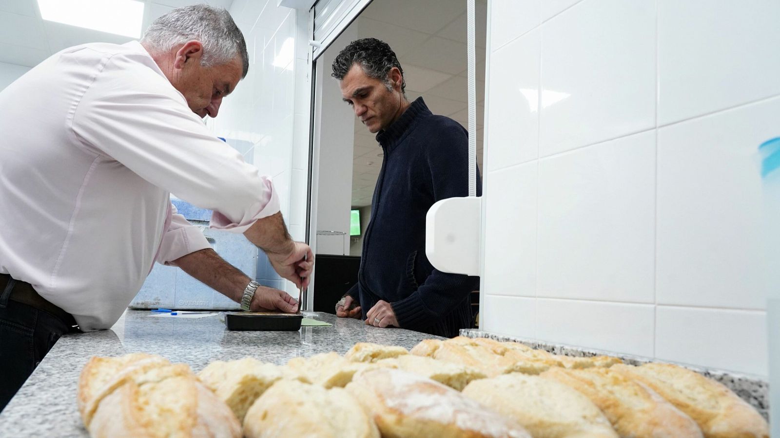 Un hombre reparte bocadillos a personas sin hogar en las instalaciones de Cáritas Valencia.