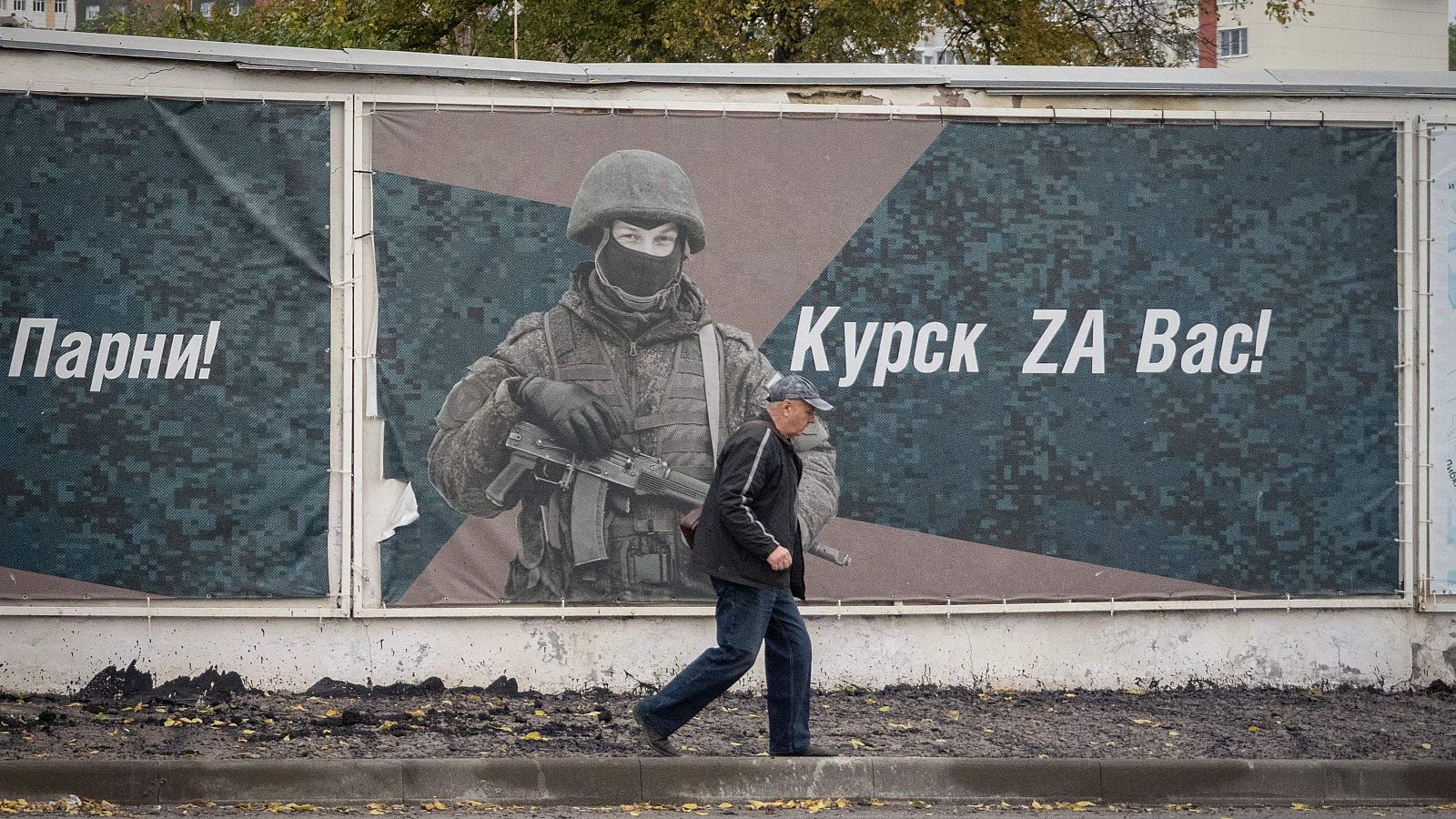 Un hombre pasa junto a una pared adornada con pancartas en honor a los militares rusos que participan en la acción militar de Rusia en Ucrania