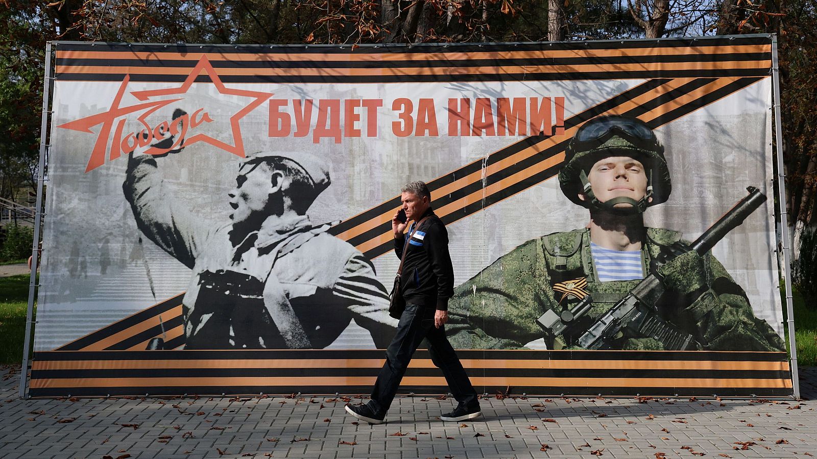 Un hombre pasa junto a una pancarta en ruso que dice "¡La victoria será nuestra!" en el asentamiento de Sovetsky, Crimea ocupada