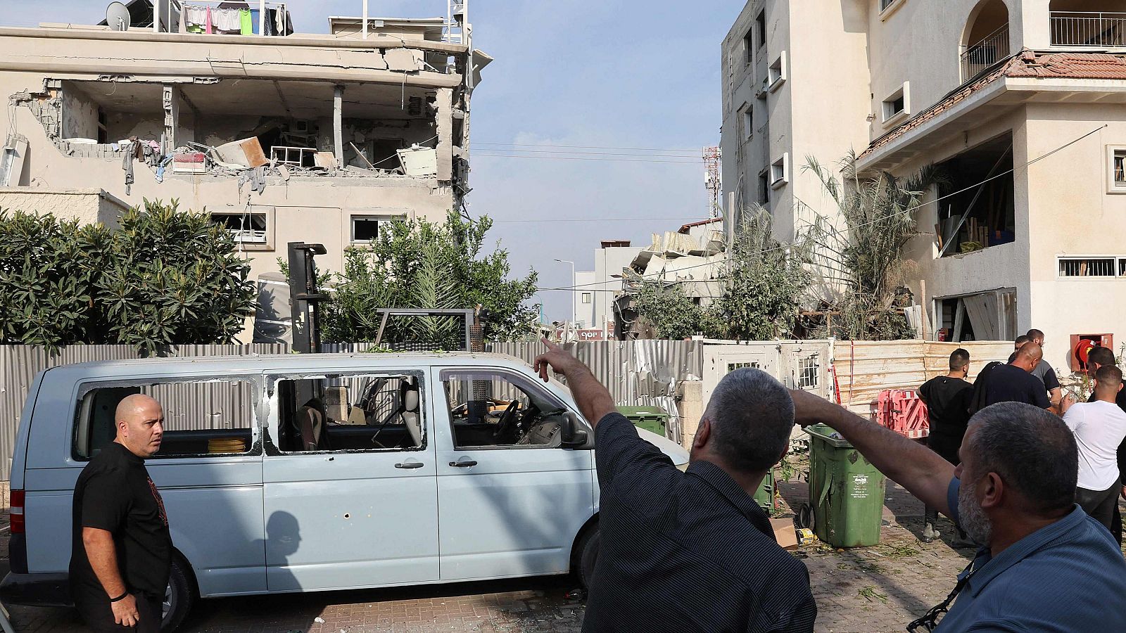 Residentes señalan un edificio dañado tras un ataque con cohetes desde el sur del Líbano. Israel ataca más de 120 "objetivos" en Gaza y Líbano, y mata a dos comandantes de Hizbulá.