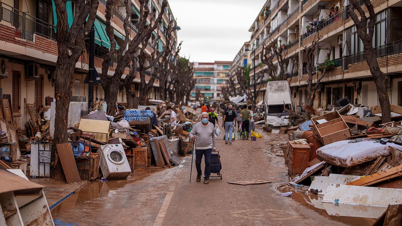 DANA, última hora en Valencia hoy: un hombre camina por una calle con muebles amontonados y basura a los lados