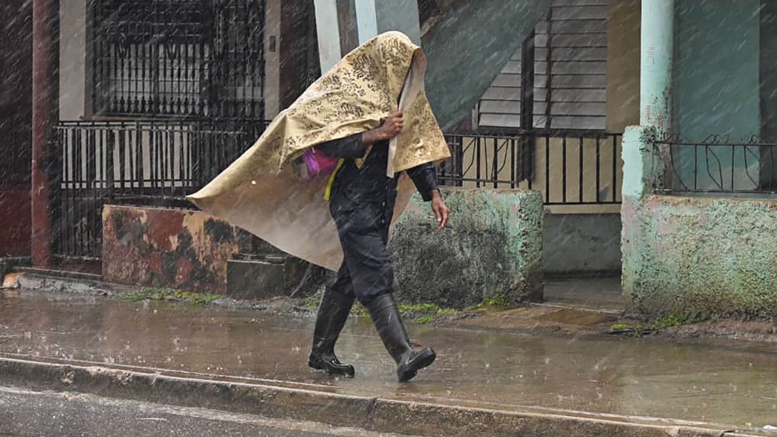 Una persona se protege de la lluvia con una tela en Artemisa, Cuba