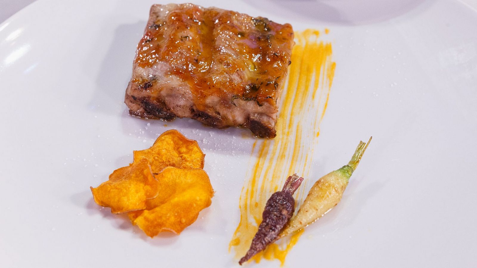 Plato de costillas con salsa de naranja, chips de boniato y zanahoria baby, elaborado por Marina Rivers en MasterChef Celebrity.