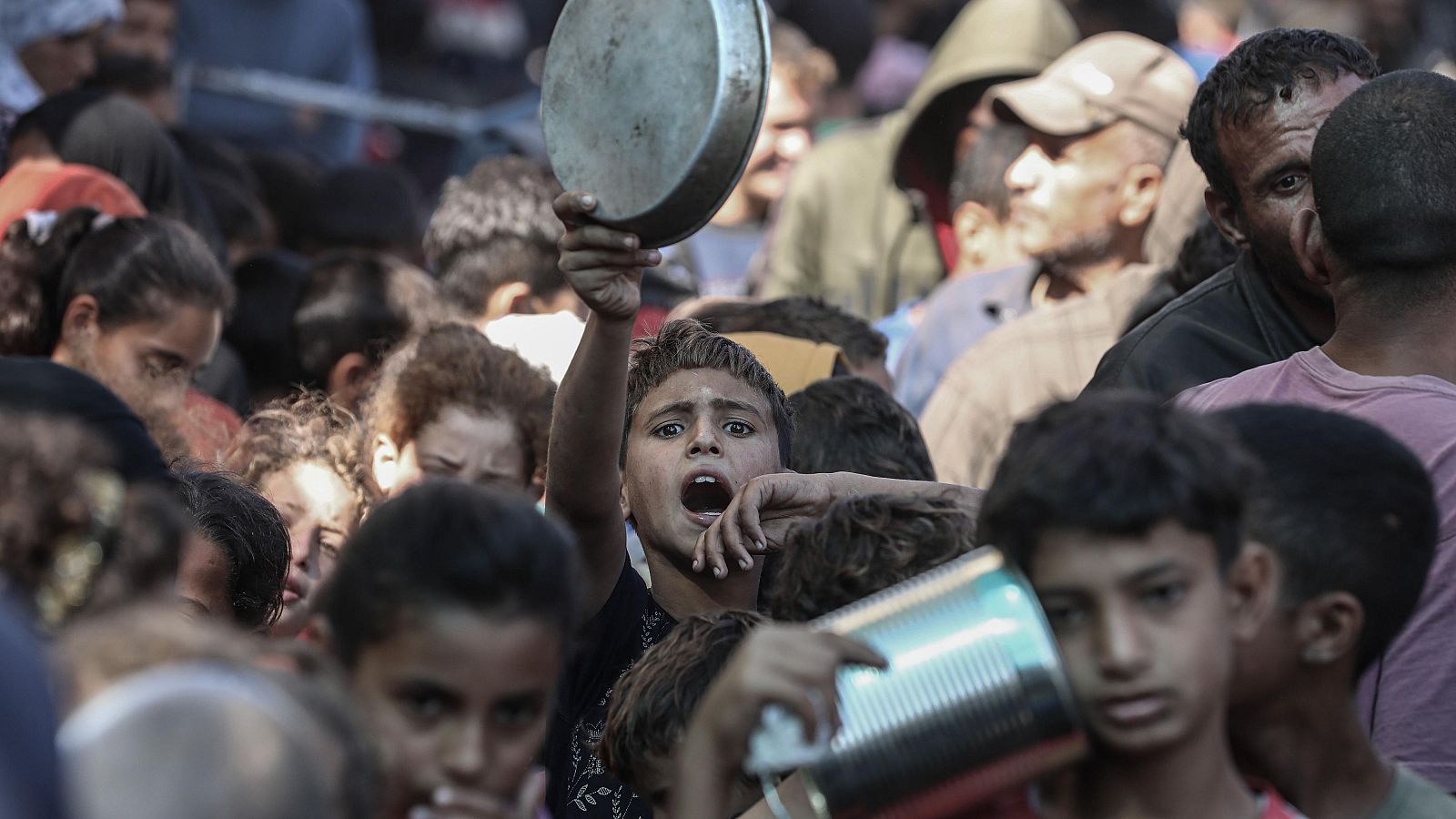 Palestinos, incluidos niños, esperan a recibir alimentos que reparte una organización de ayuda en Deir al Balah, Gaza