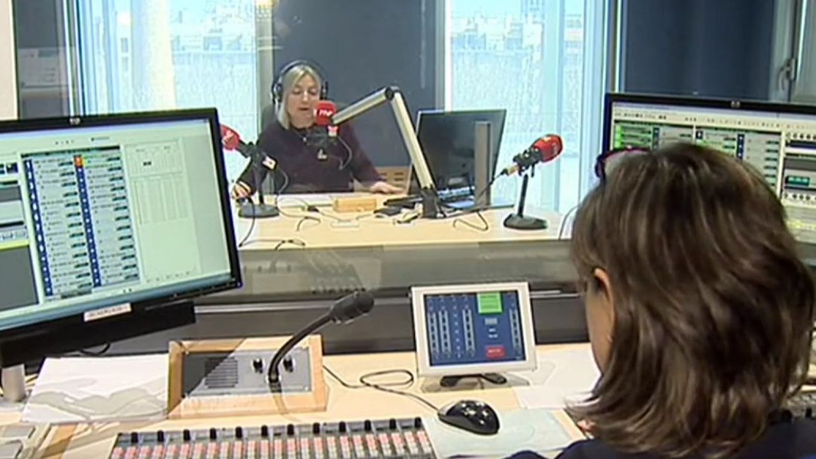 Dos mujeres trabajan en un estudio de radio con micrófonos, ordenadores y una mesa de mezclas.