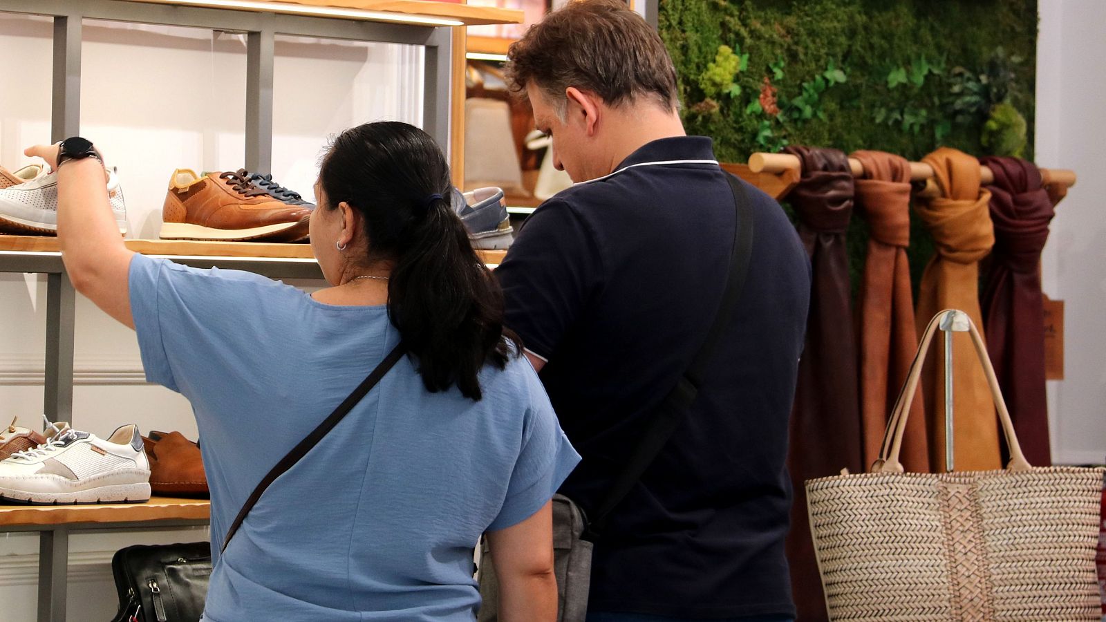 Una mujer y un hombre miran zapatos en una tienda.