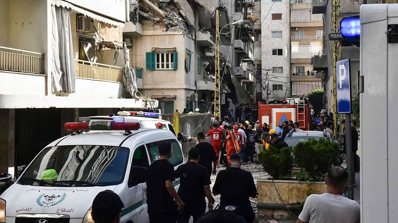 Daños en un edificio de Beirut tras un ataque israelí, con equipos de rescate y civiles presentes.