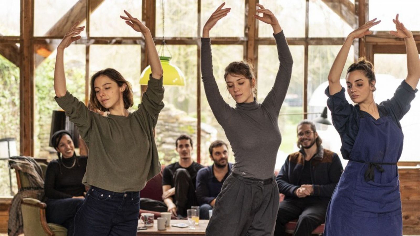 Tres bailarinas ensayan en una sala rústica, mientras otros observan. Avance de "Un paso adelante" en La 2.