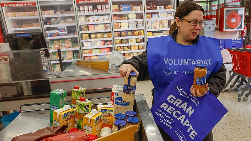 Voluntaria de FESBAL colocando alimentos en una cinta transportadora de supermercado durante la Gran Recogida de Alimentos.
