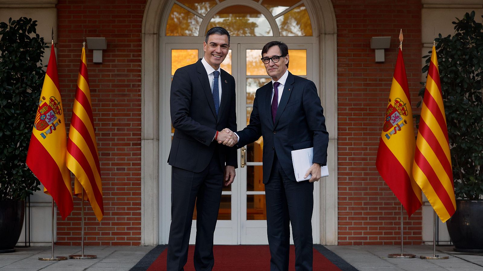 Encuentro entre Pedro Sánchez y Pere Aragonès en la Moncloa.  Se estrechan la mano en la entrada, con banderas españolas y catalanas presentes.