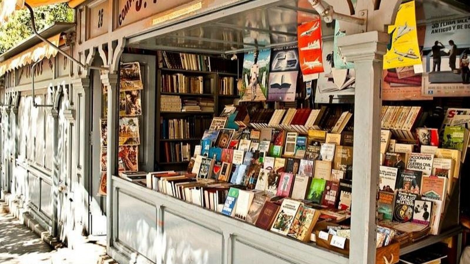 Vista de la Cuesta de Moyano en Madrid: casetas de libros grises con toldos beige, mostrando una gran variedad de títulos.