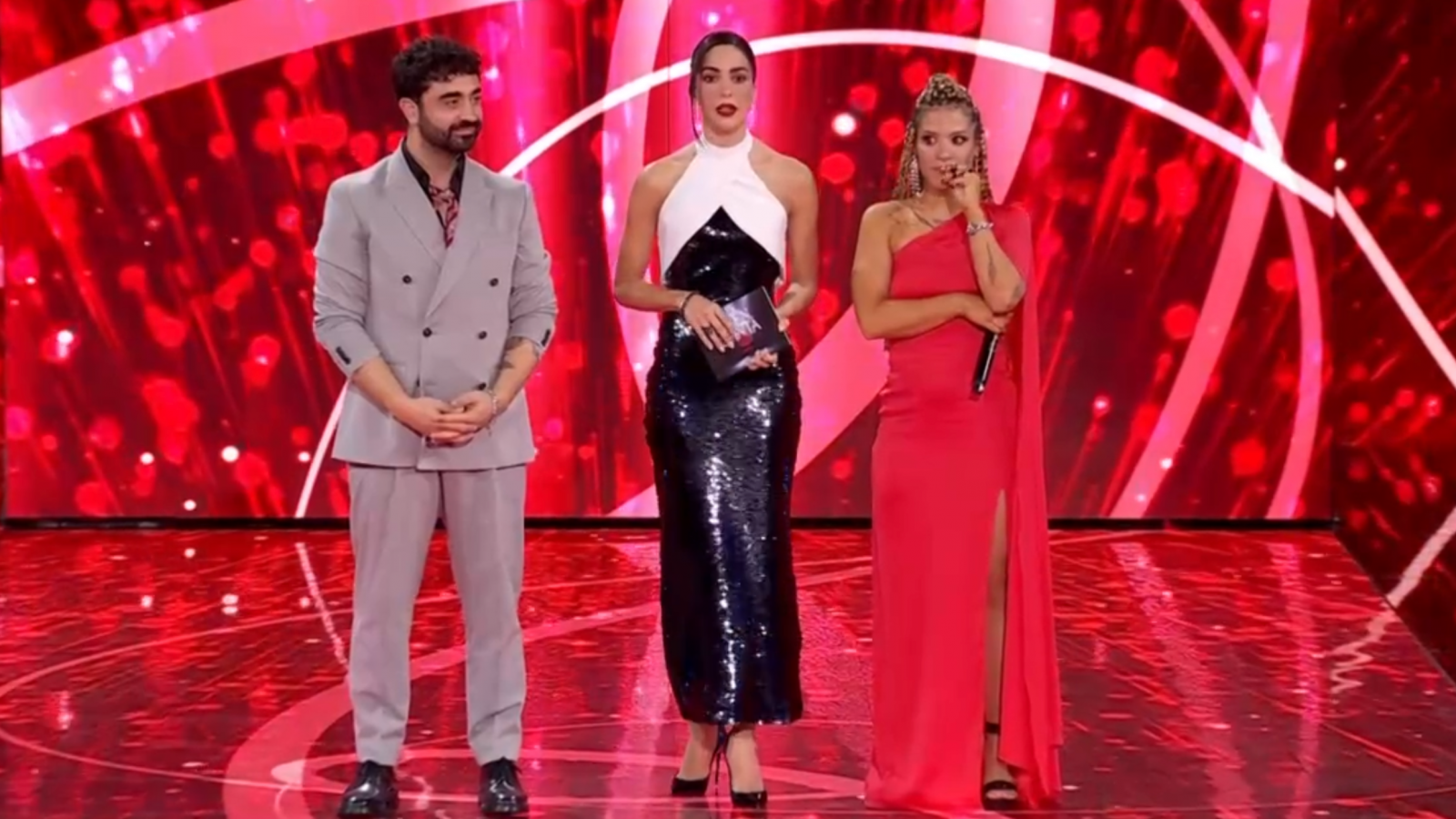 Marazu y Alba Dreid, finalistas de 'La Bien Cantá', en el escenario con otra mujer.  Trajes elegantes, escenario rojo brillante.