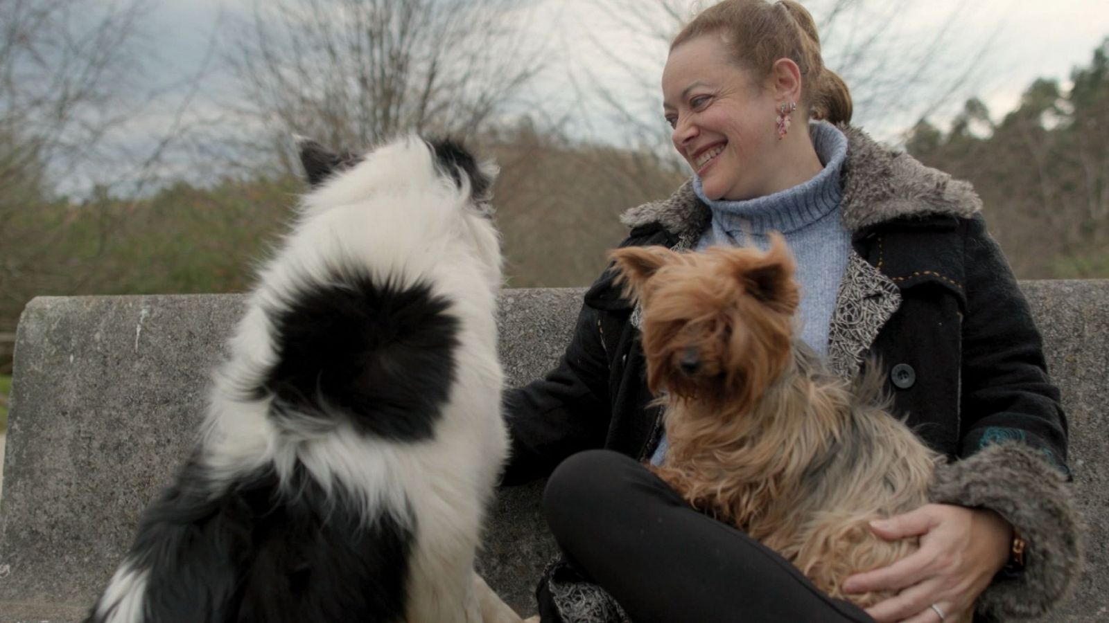 Arancha Barreiro sonríe junto a dos perros en un parque.  Uno es blanco y negro, el otro marrón.  La imagen transmite normalidad a pesar del titular sobre el VIH.