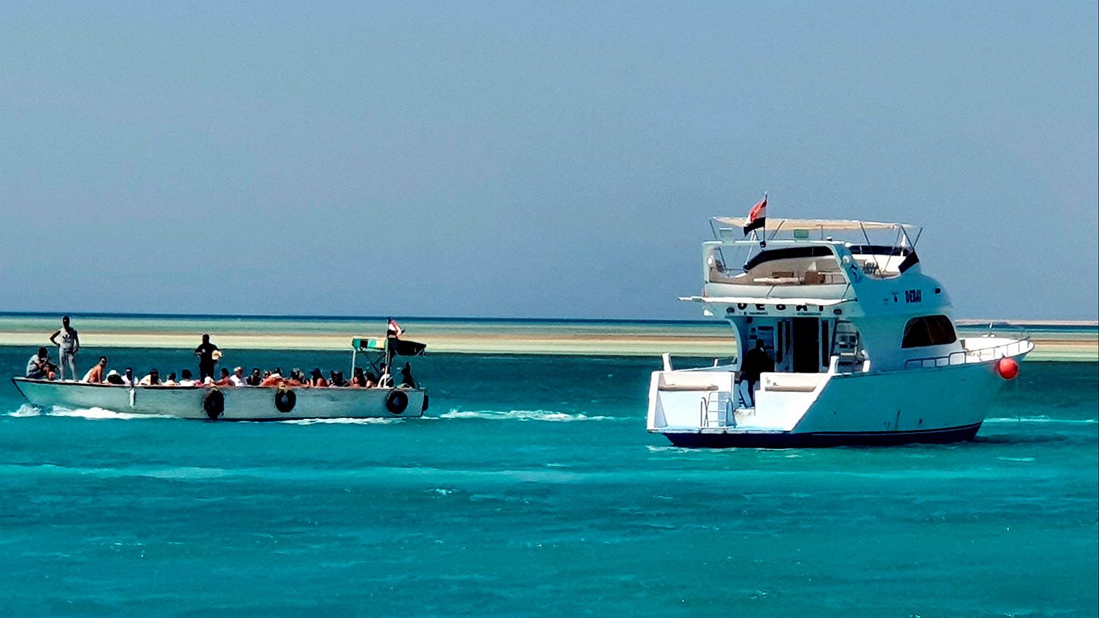 Turistas en un bote junto a un yate atracado en el puerto de Hurghada, en el mar Rojo