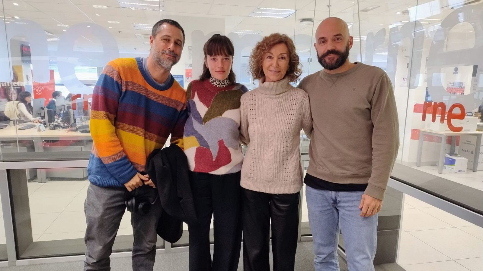 Cuatro personas (dos hombres, dos mujeres) posan para una foto en un estudio de radio, posiblemente de RNE, cuyo logo se ve al fondo.