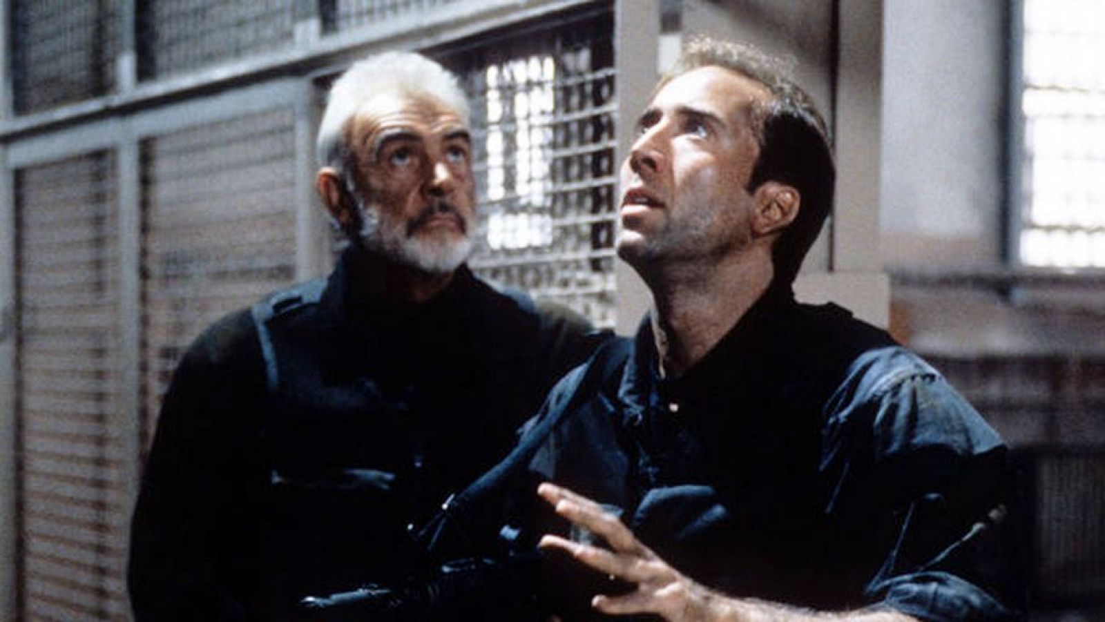 Nicholas Cage y Sean Connery en una escena de 'La Roca'.  Ambos miran hacia arriba con expresiones preocupadas en un ambiente carcelario.