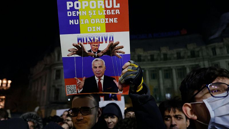 Protesta en Rumanía contra la influencia rusa en las elecciones. Cartel con Putin y Ciolacu como marionetas, mensaje: "El pueblo digno y libre no recibe órdenes de Moscú".