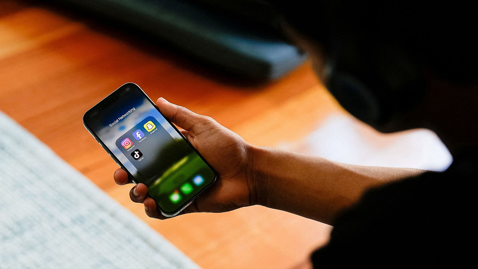 Un estudiante de secundaria posa con su teléfono móvil mostrando sus aplicaciones de redes sociales