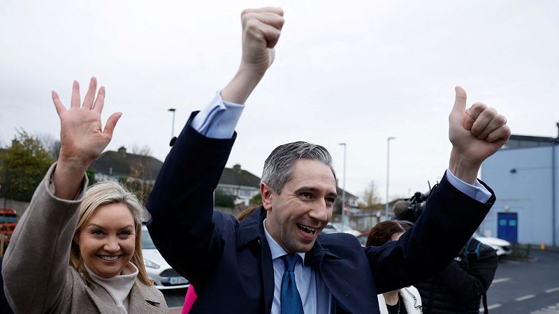 El primer ministro irlandés Simon Harris, con los brazos en alto y una gran sonrisa, participa en un animado acto de campaña.